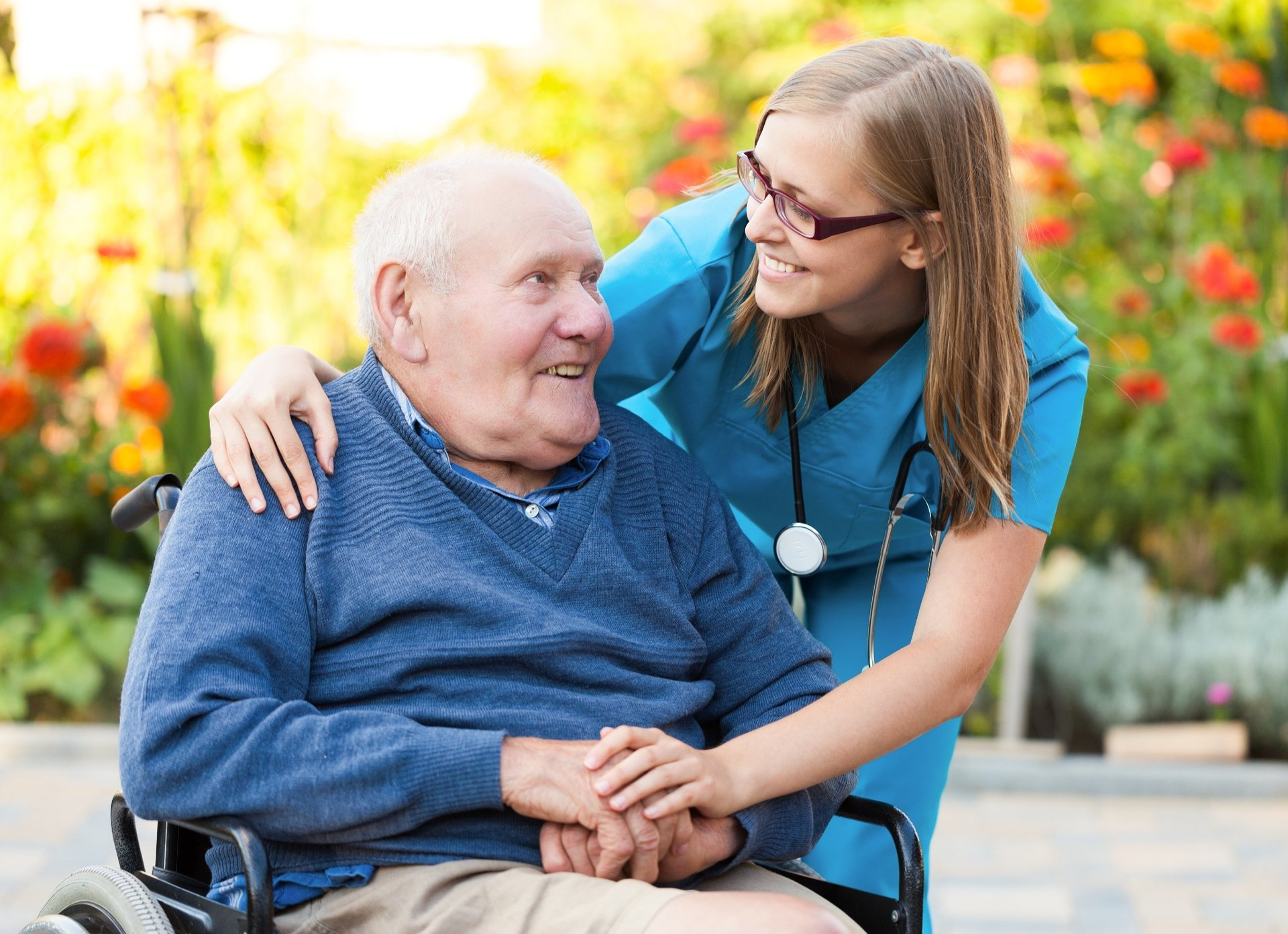 Smiling older man in wheelchair being assisted by careworker