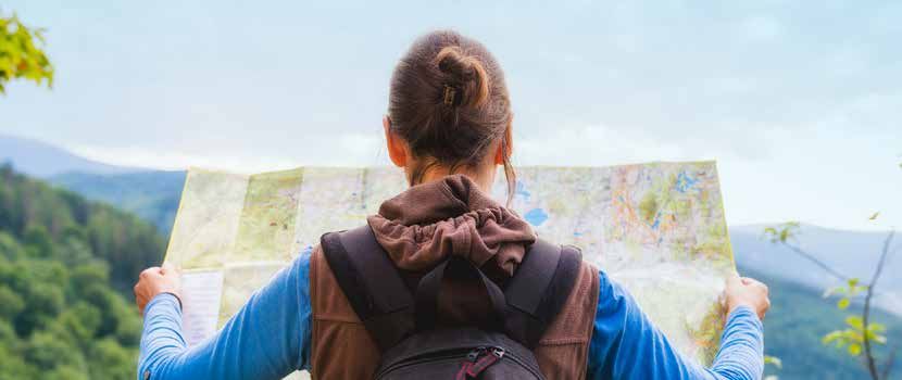 A woman in walking gear holds a large map out in front of her