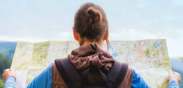 A woman in walking gear holds a large map in front of her