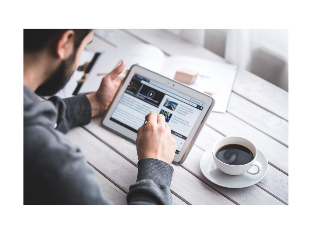 Dekoratives Element Mann sitzt am Tisch mit einer Tasse Kaffee und liest in einem Tablet