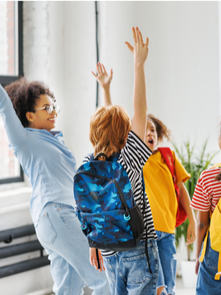 Lehrerin mit Kindern, die jubelnd die Arme hochstrecken