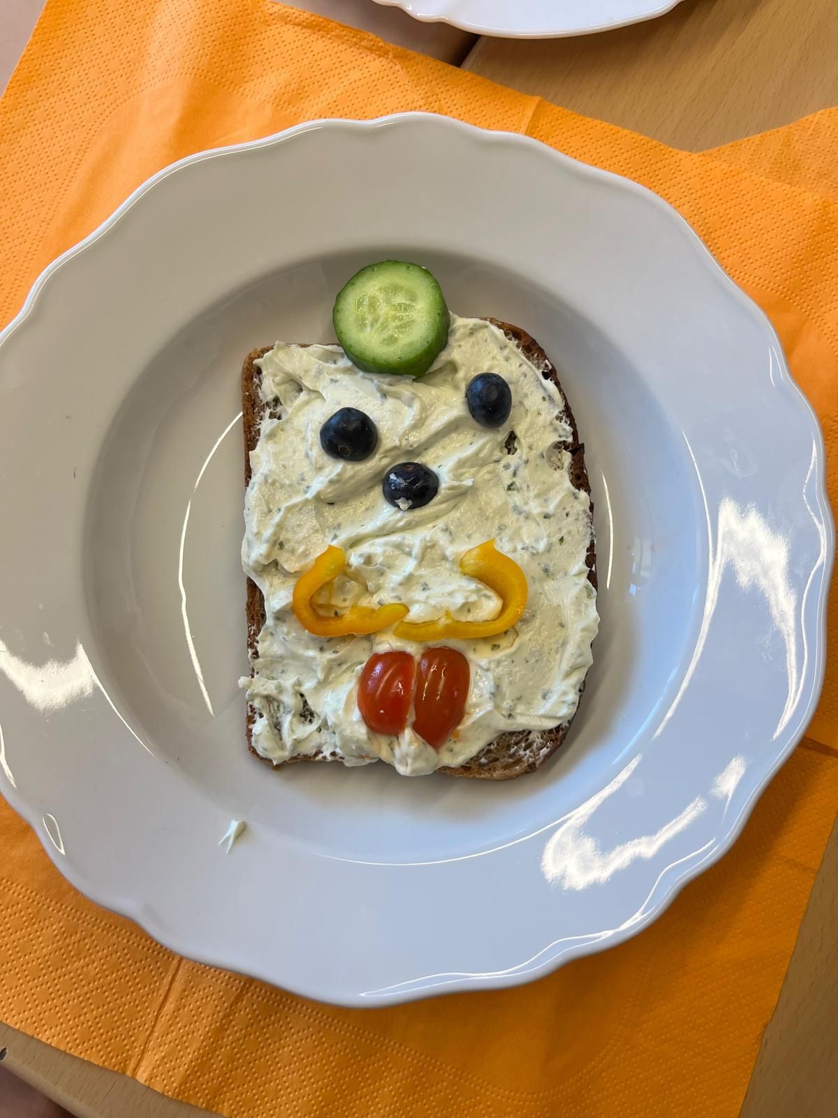 belegtes Toastbrot dessen Belag aus Gemüse zu einem Smiley belegt ist