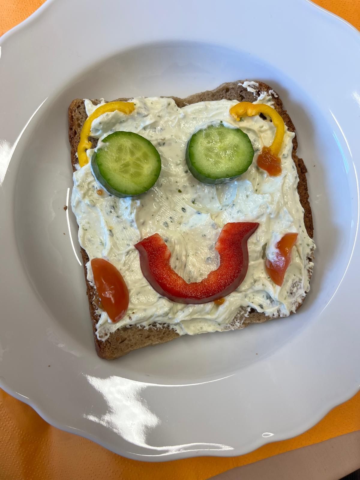 belegtes Toastbrot dessen Belag aus Gemüse zu einem Smiley belegt ist