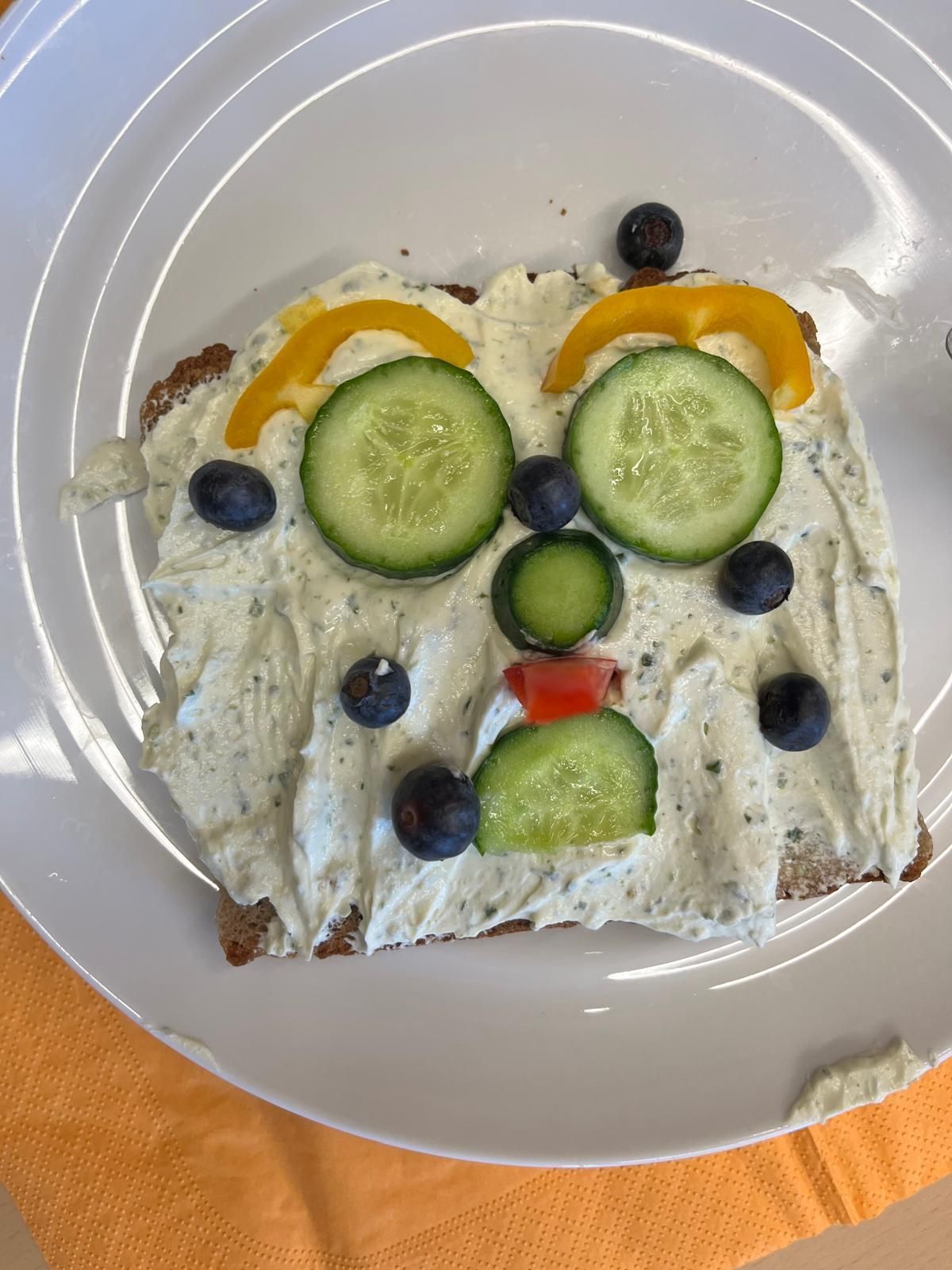 belegtes Toastbrot dessen Belag aus Gemüse zu einem Smiley belegt ist