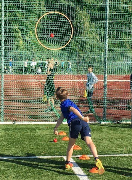Junge wirft auf Sportplatz Ball über ein Netz
