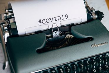 ancienne machine à écrire avec le mot #COVID19 inscrit sur un papier blanc
