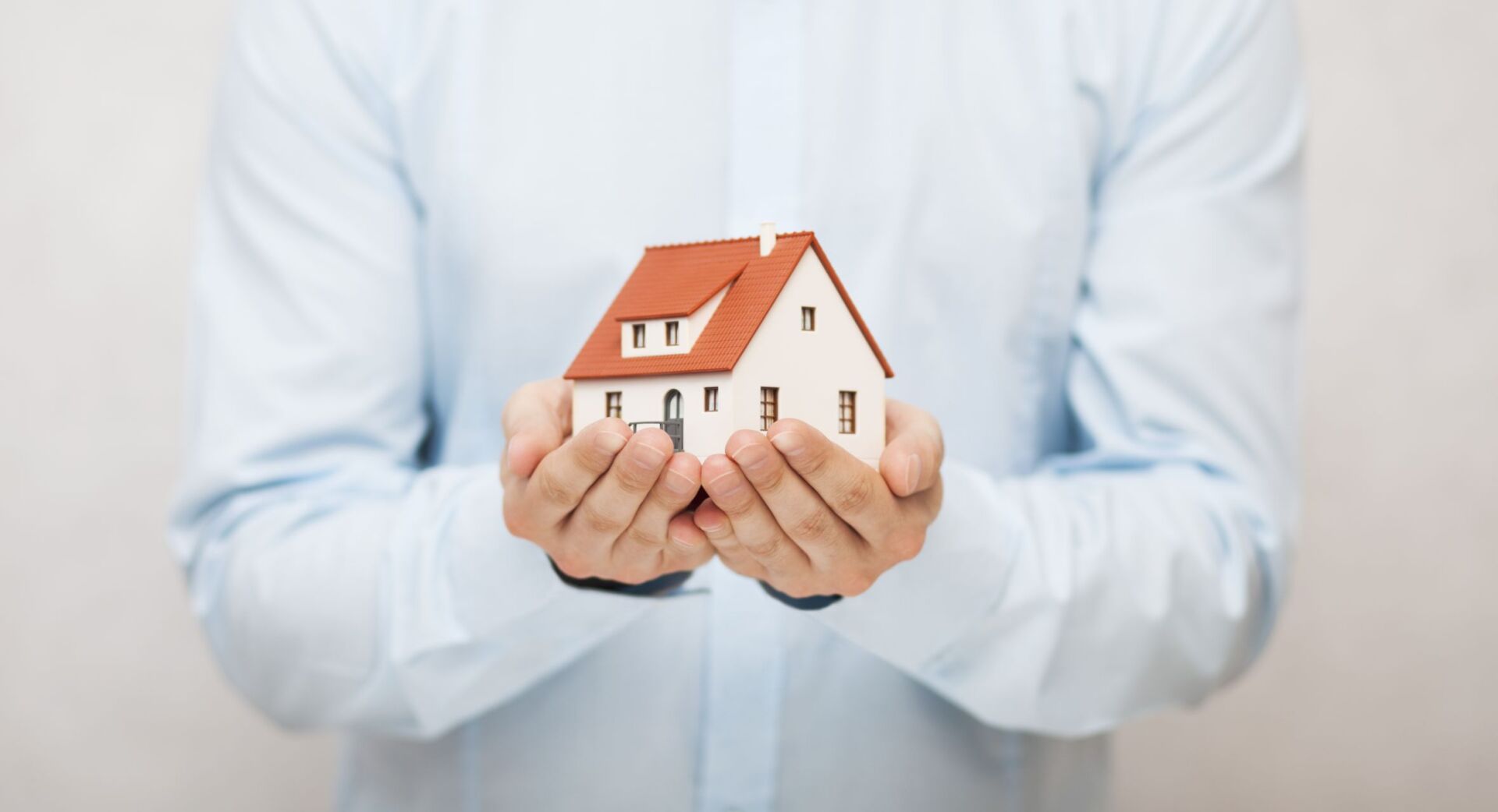 a person holding a model home in their hands