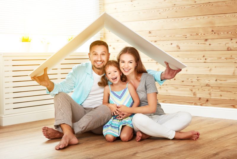 a smiling family with a cardboard roof over their heads