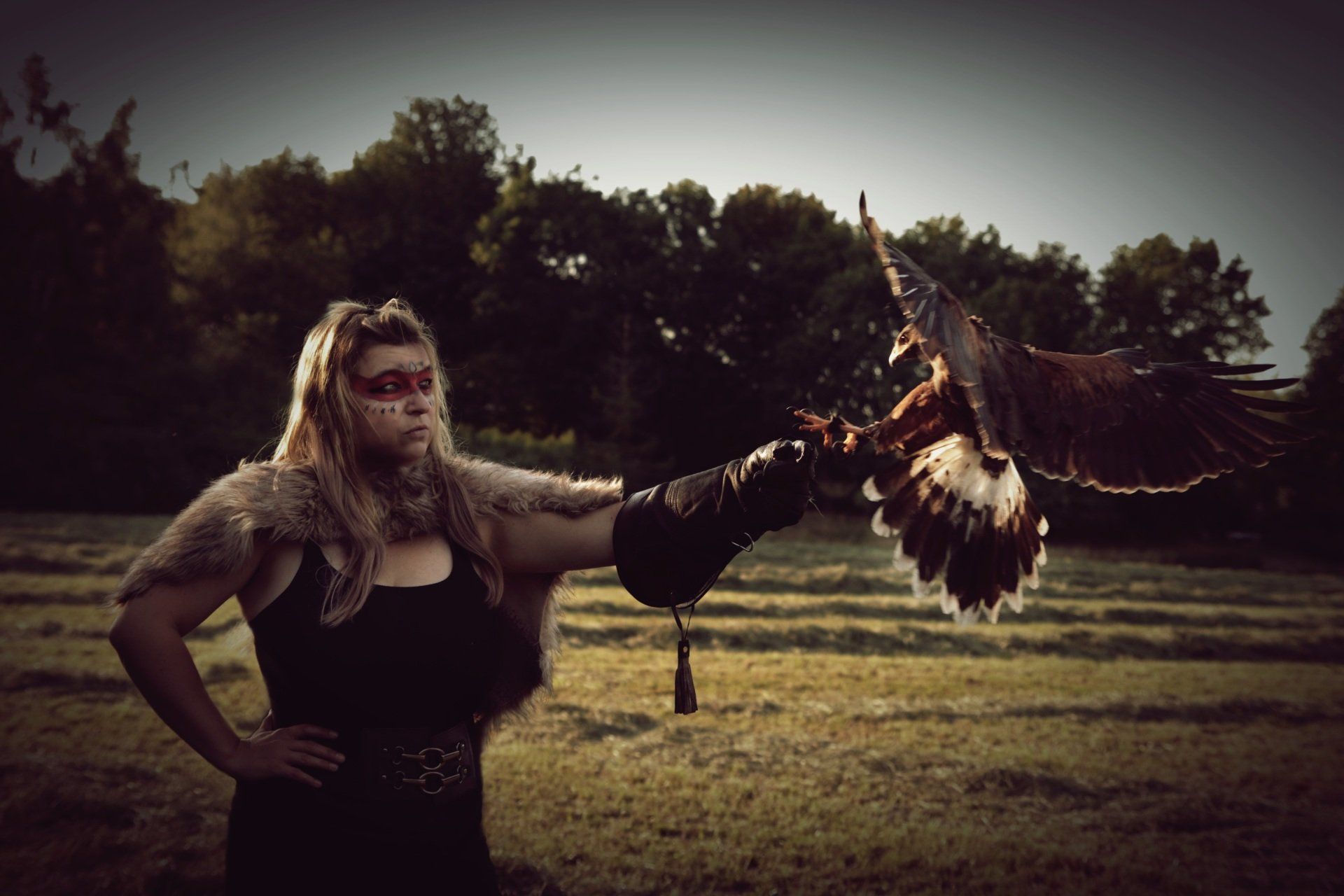 Greifvogel fliegt einer Frau im indigenen Look auf die Faust.