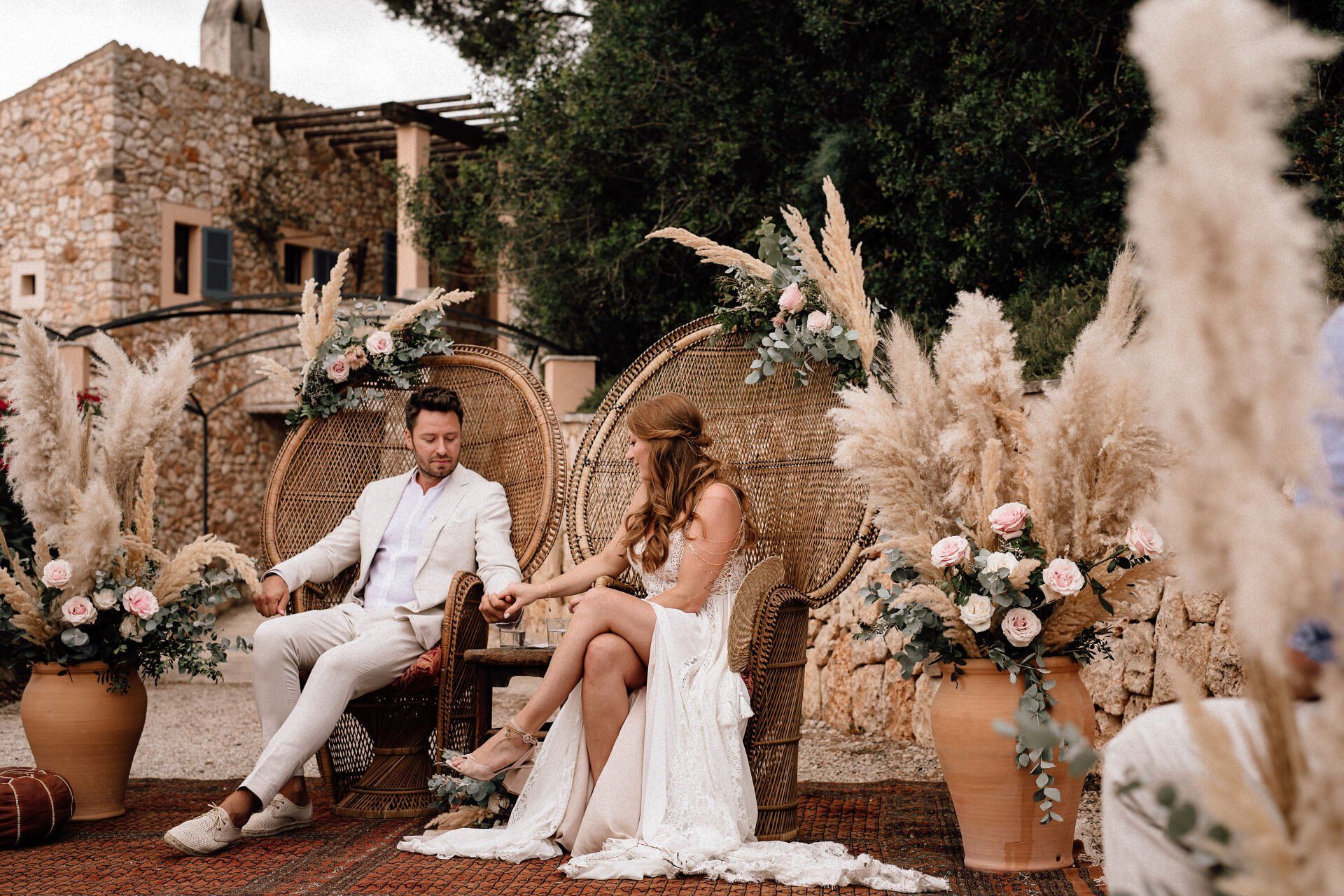 Brautpaar hat zur freien Trauung auf Mallorca in Pfauenstühlen Platz genommen