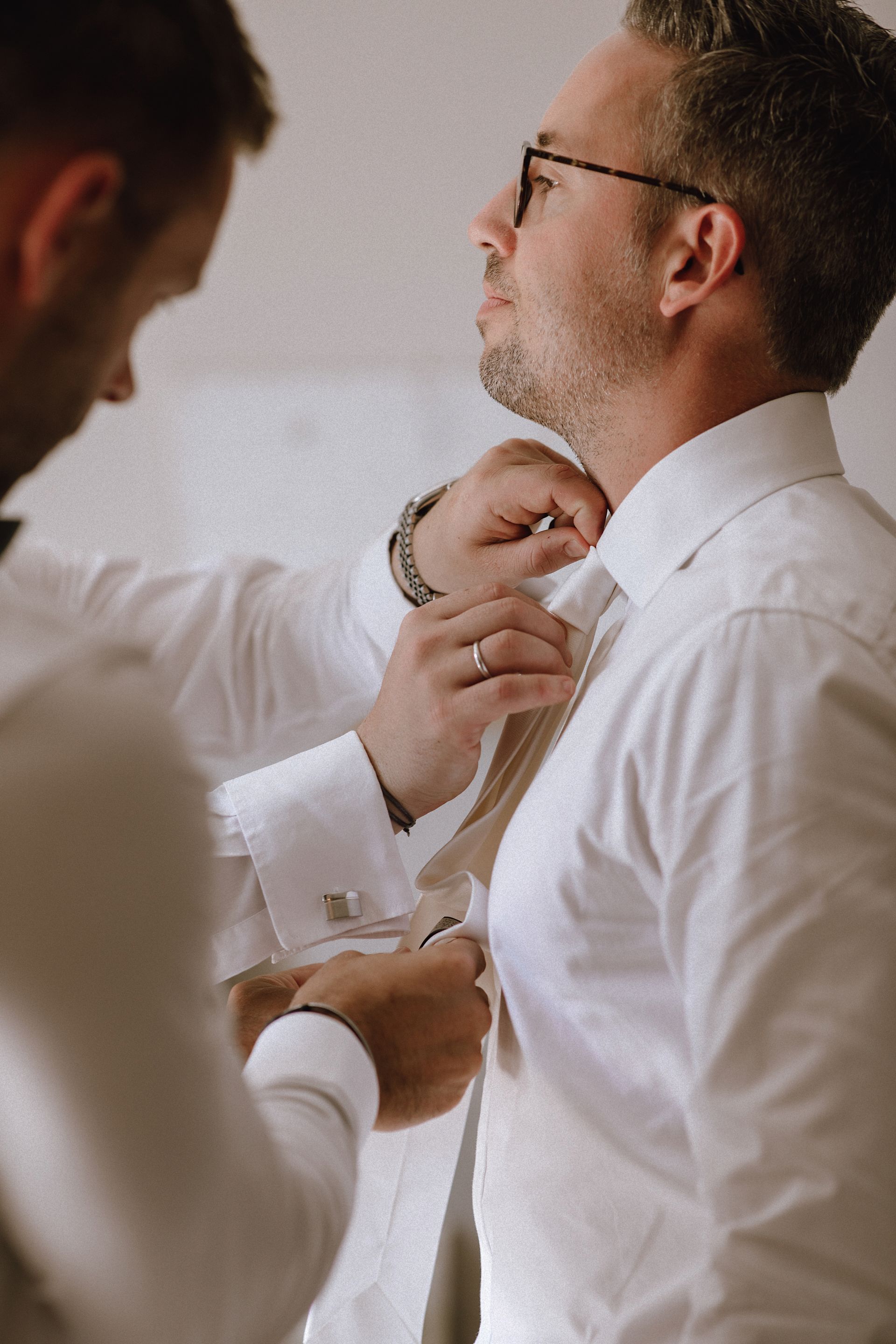 Bräutigam wird beim Getting Ready von seinen Freunden unterstützt, die ihm die Krawatte binden.