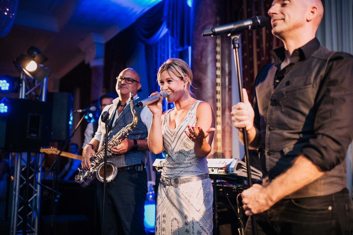 Bandleaderin Annekatrin Schmid steht in der Mitte der Bühne gemeinsam mit einem Saxophonisten und einem weiteren Sänger.