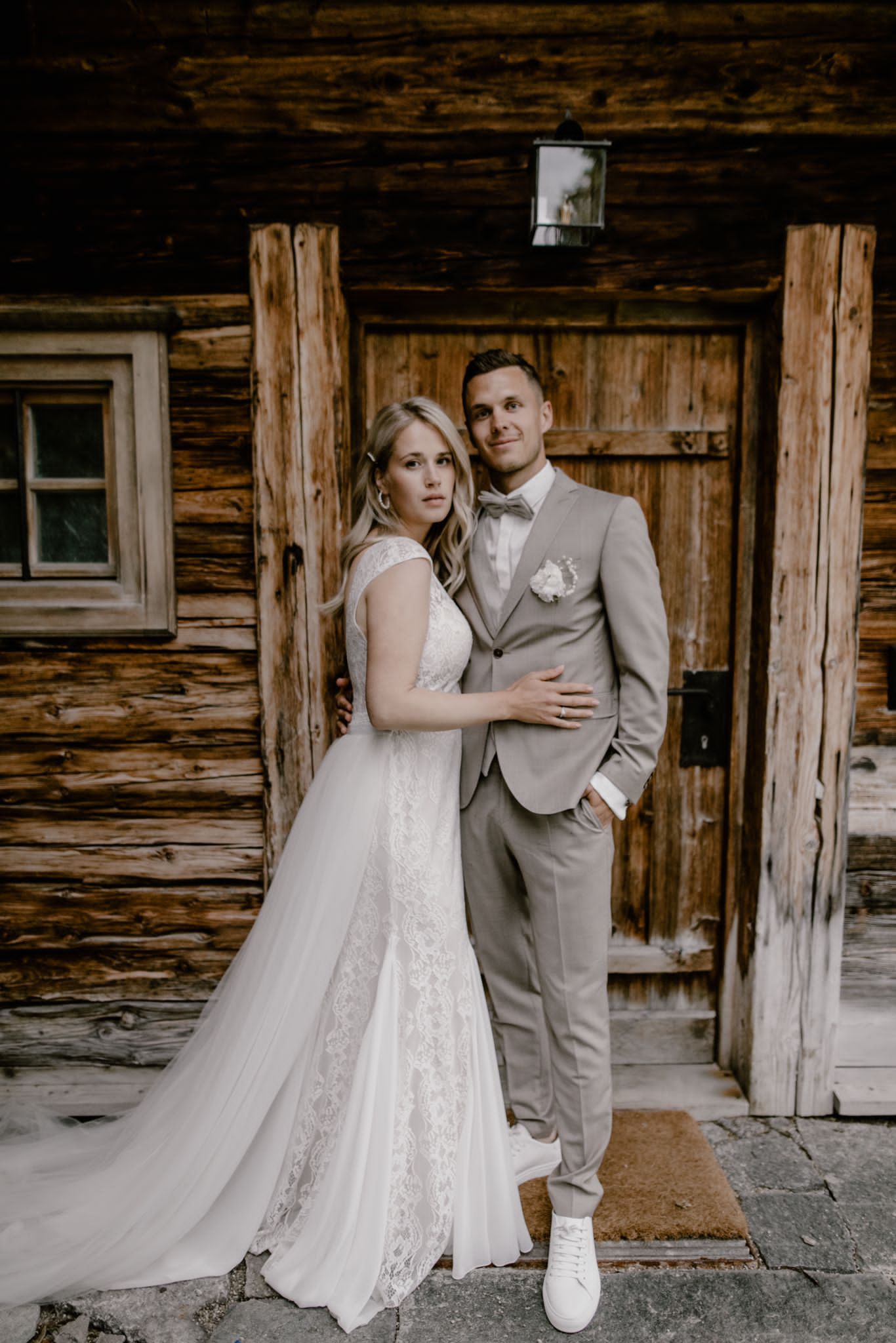 Ein Brautpaar steht nach der Freien Trauung vor der Tür einer bayrischen Berghütte.