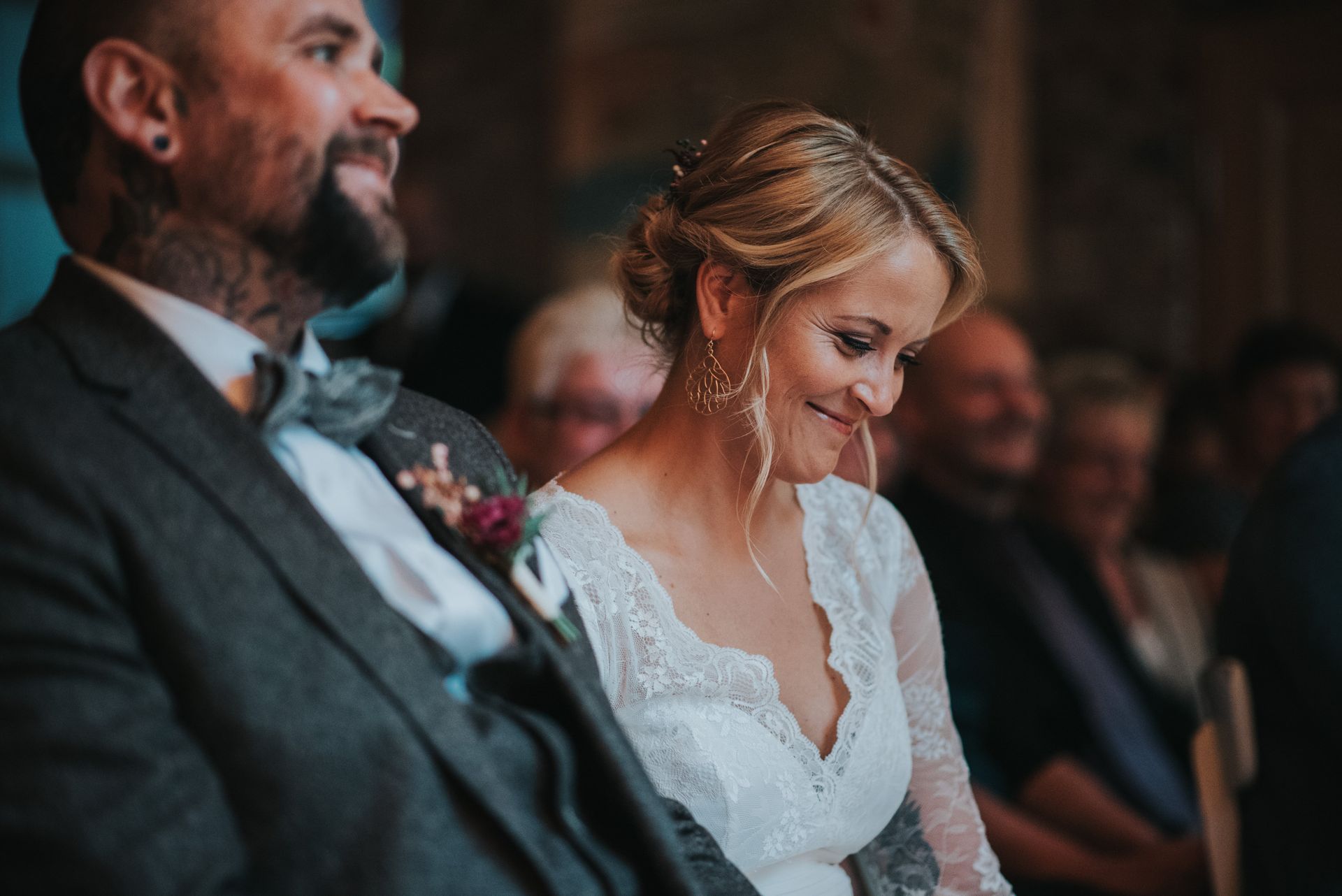 Das Brautpaar hört der Traurednerin bei der Freien Trauung andächtig zu. Die Braut schmunzelt lächelnd in sich hinein.