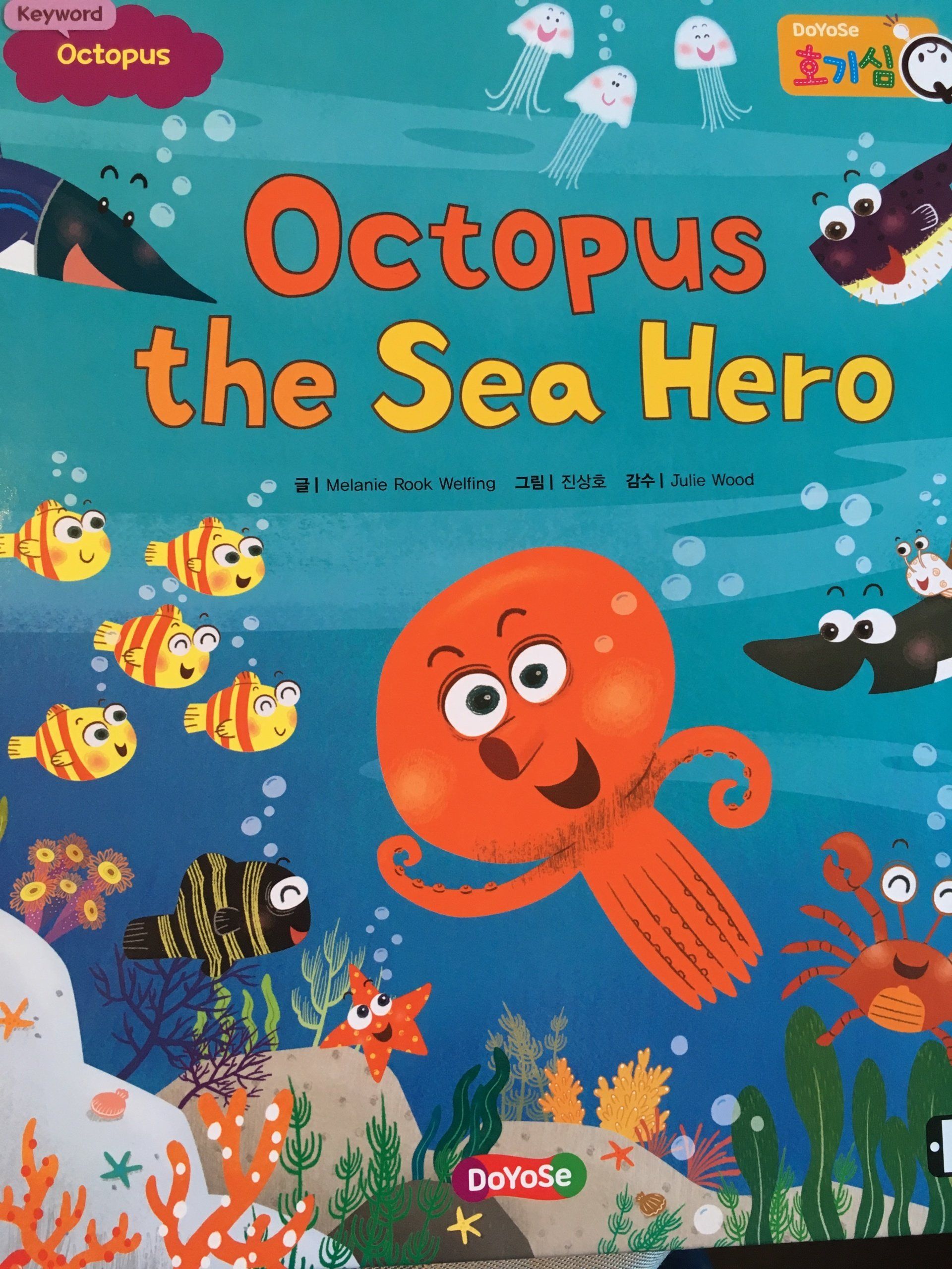 A picture of fish swimming in the sea with rocks and seaweed. An octopus cartoon is smiling and waving. Title: Octopus the Sea Hero by Melanie Rook Welfing.